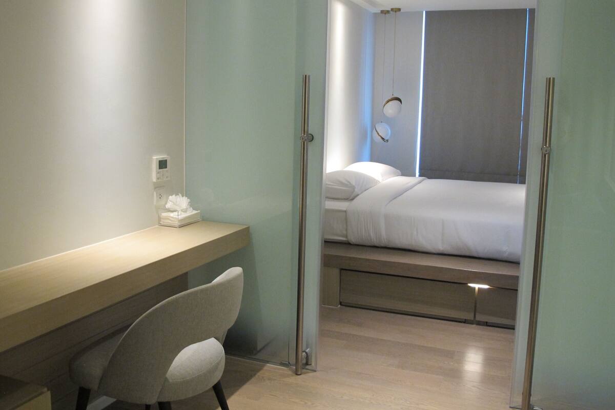 Quarto de hotel moderno com cama, escrivaninha e cadeira.