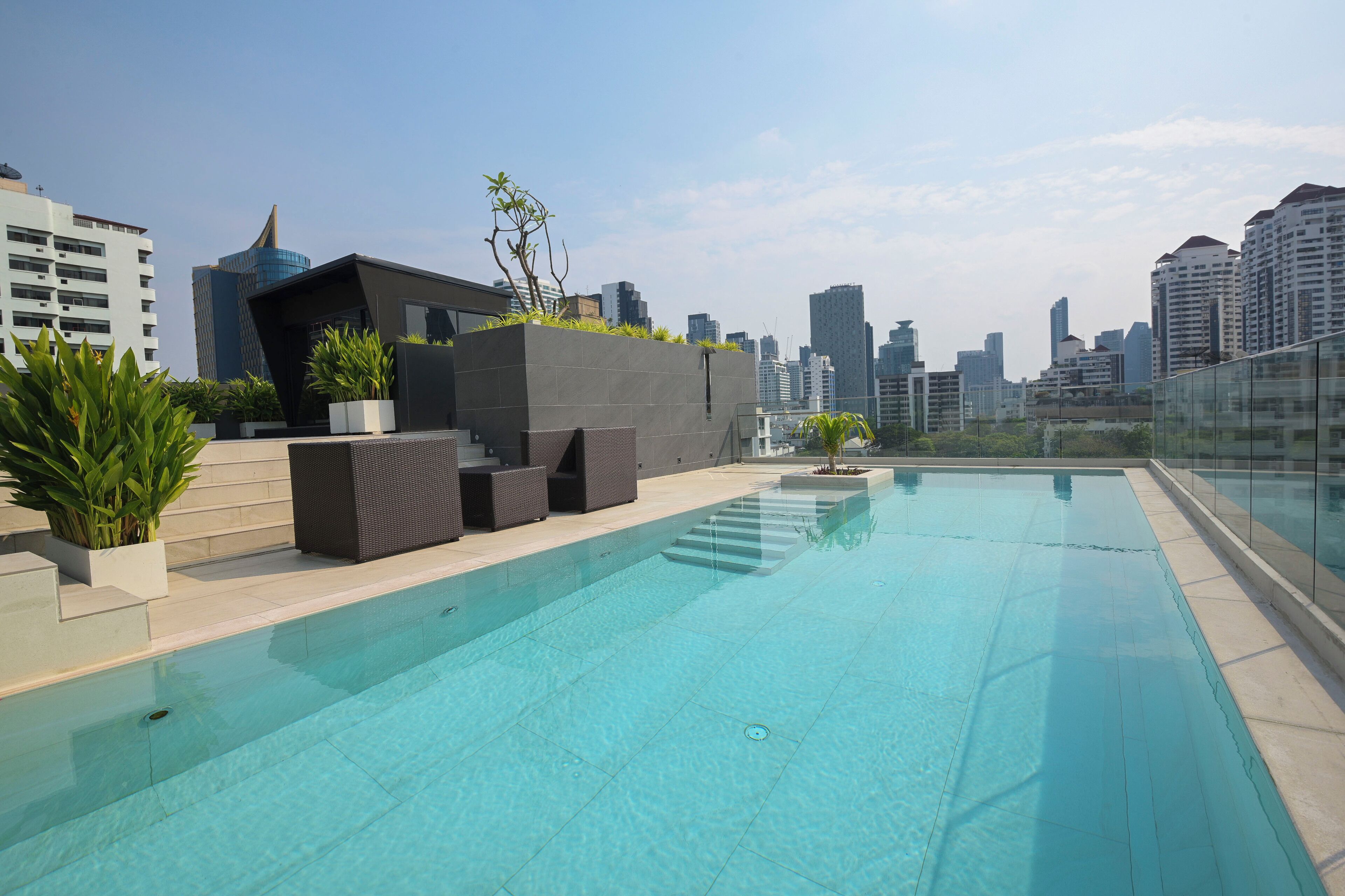 A rooftop swimming pool with a city skyline in the background.