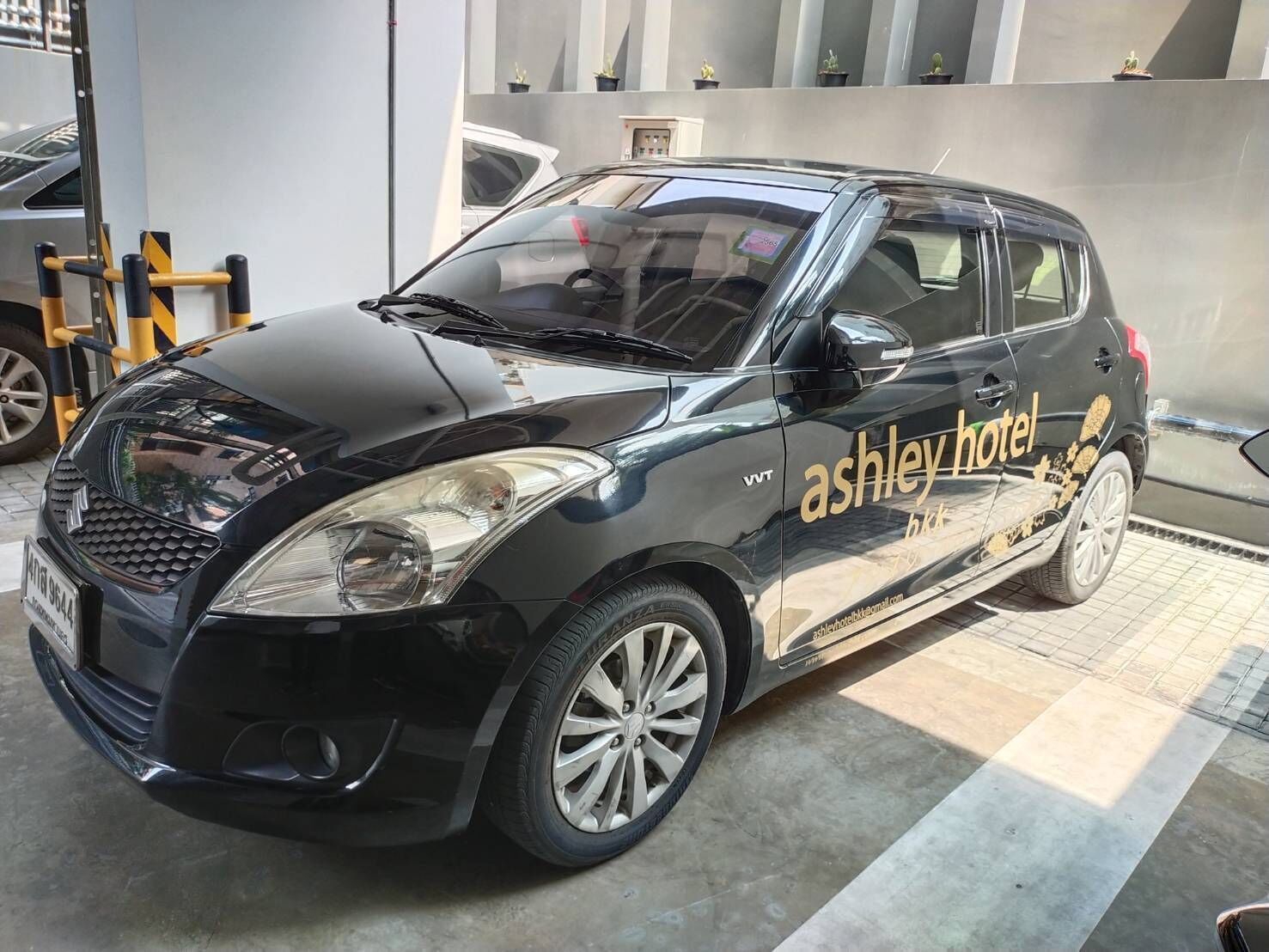Une voiture noire, portant l’inscription « Ashley Hotel », est garée dans un garage.