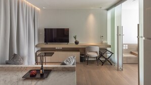Ein modernes Wohnzimmer mit Flachbildfernseher, einer Couch, einem Couchtisch und einer Glastür, die auf einen Balkon führt.