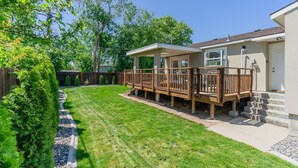 A residential property with a covered deck, a well-maintained lawn, and a wooden fence. - 4-bedroom vacation home just 15 minutes to Columbia River (Richland)