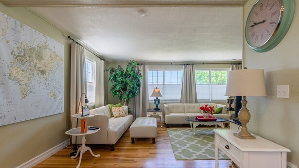 A living room with a large world map, a white sofa, a coffee table, and a lamp. - 4-bedroom vacation home just 15 minutes to Columbia River (Richland)
