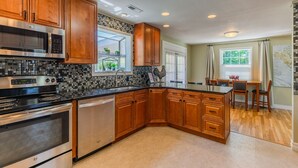 A modern kitchen with wooden cabinets, a stainless steel stove, and a tiled backsplash. - 4-bedroom vacation home just 15 minutes to Columbia River (Richland)