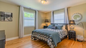 A bedroom with a bed, two bedside tables, a lamp, a mirror, and a painting on the wall. - 4-bedroom vacation home just 15 minutes to Columbia River (Richland)