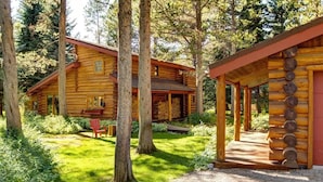A log cabin with a porch, surrounded by trees and a well-maintained lawn. - Abode at the Aspens, hot tub, near Teton Village (Wilson)