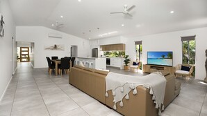 Uma sala moderna com sofá, área de jantar, cozinha e televisão.