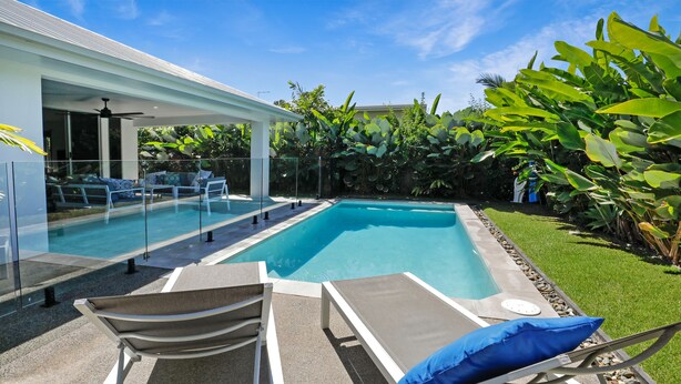 Piscina com espreguiçadeiras e área de estar coberta.