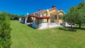 Une maison à deux étages avec un toit rouge, une terrasse couverte et une pelouse bien entretenue.