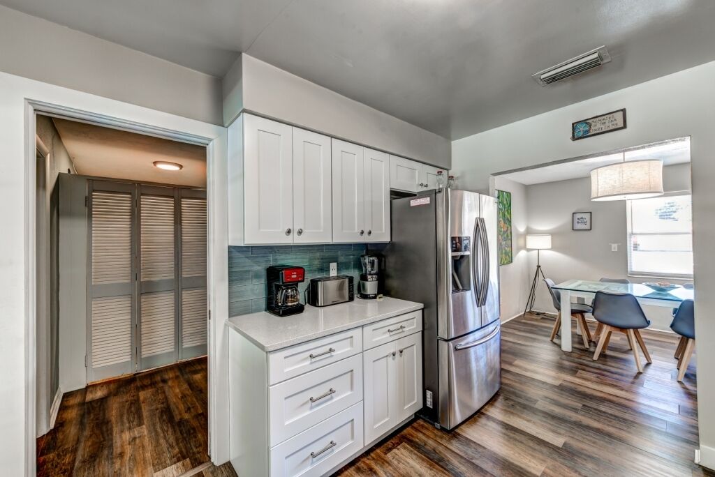 A compact kitchen with white cabinets, a stainless steel refrigerator, and a coffee maker.