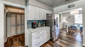 A compact kitchen with white cabinets, a stainless steel refrigerator, and a coffee maker.