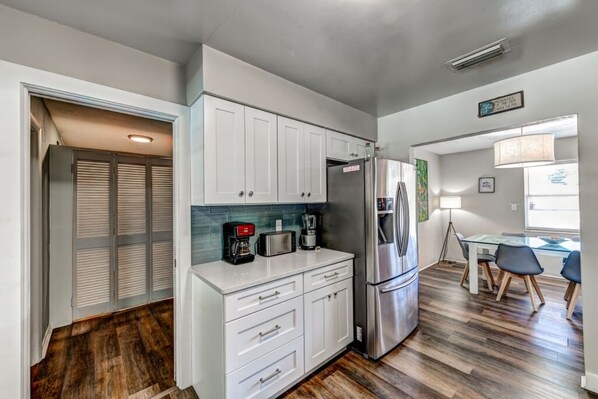 A compact kitchen with white cabinets, a stainless steel refrigerator, and a coffee maker.