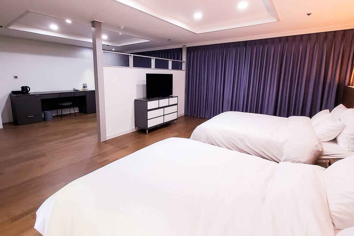 Une chambre d’hôtel moderne dotée d’un grand lit, d’un bureau avec une télévision et d’un coin salon séparé.