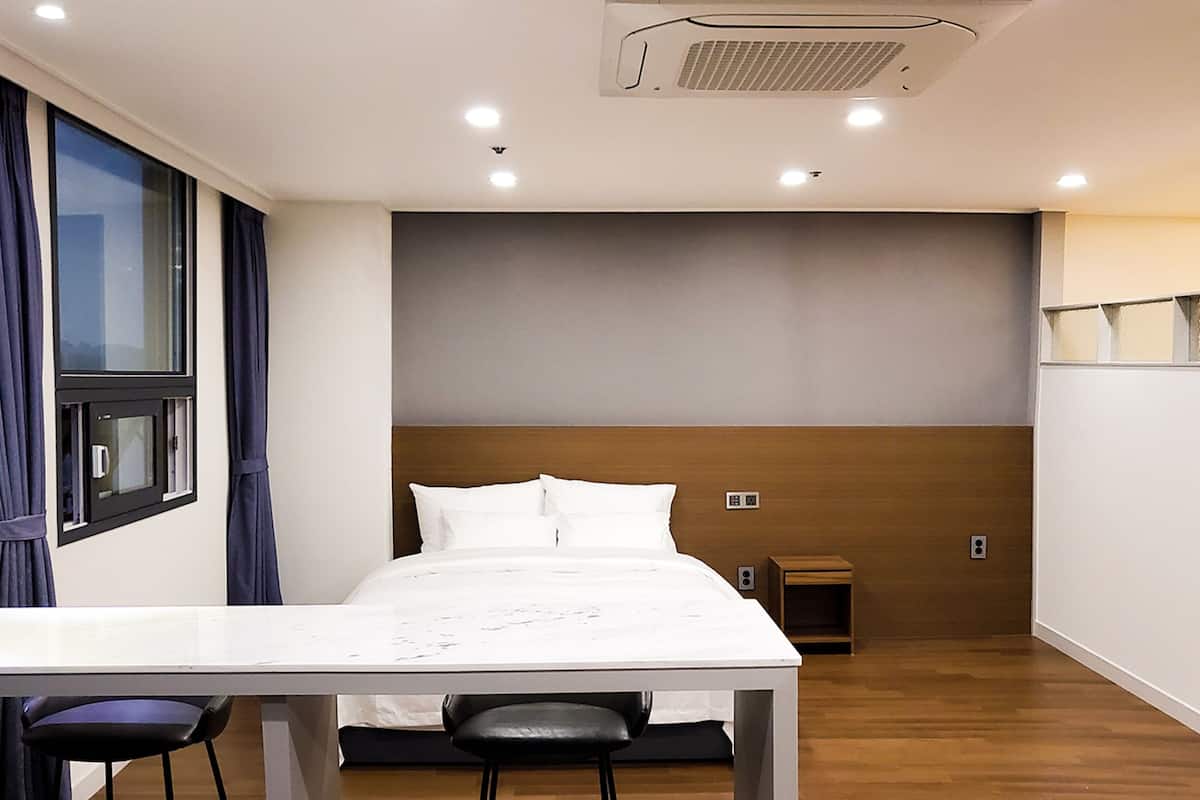 Une chambre d’hôtel moderne, équipée d’un lit, d’un bureau et de chaises.