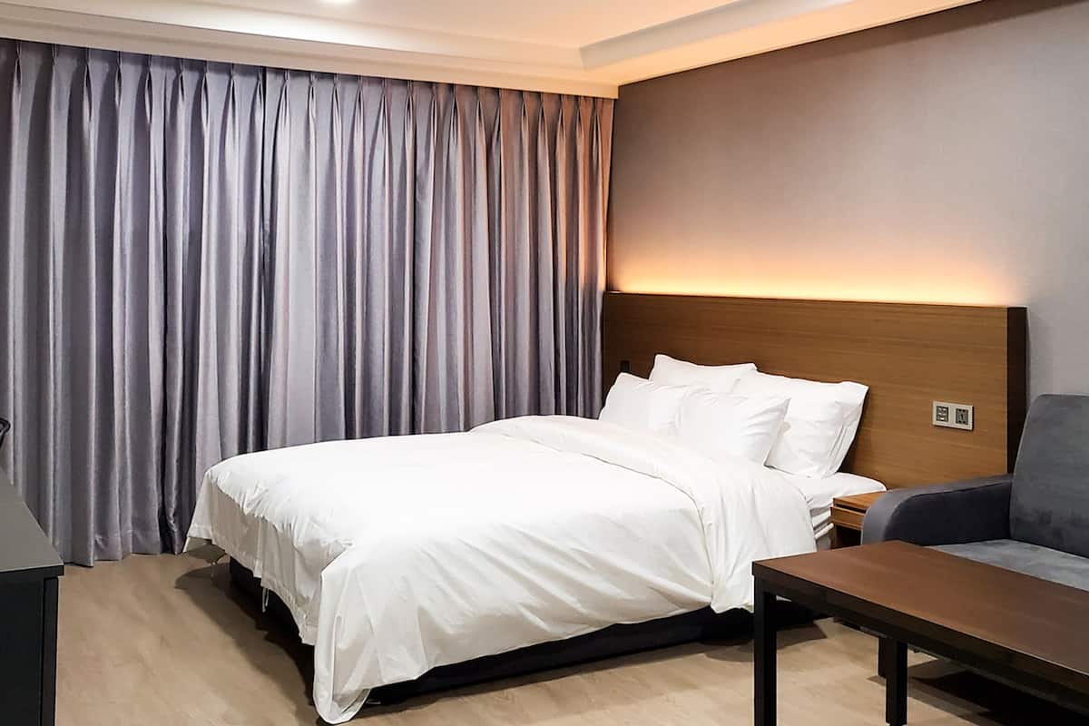 Une chambre d’hôtel avec un lit, une table de chevet, un bureau et un canapé.