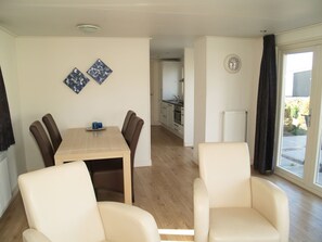 A modern living room with a dining table, two chairs, and a kitchen in the background. - Comfortable Chalet Near Brunssummerheide (Brunssum)