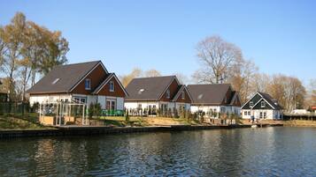 A row of houses by a calm lake with a clear sky.