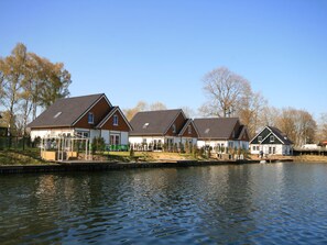 A row of houses by a calm lake with a clear sky.