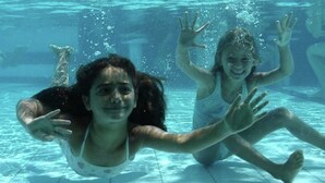Twee kinderen zwemmen onderwater in een zwembad.