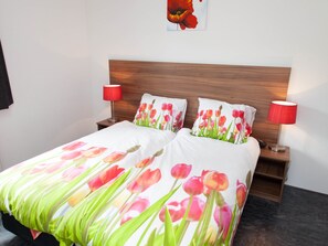 A neatly made bed with a floral duvet cover, two bedside lamps, and a wooden headboard.