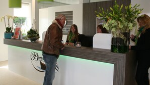 Un mostrador de recepción con un logotipo, una planta en maceta y una lámpara colgante verde.