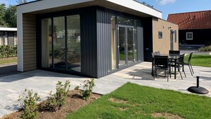 Ein modernes Haus mit Terrasse, inklusive Tisch und Stühlen.