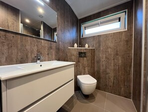 Un bagno con un lavandino bianco capiente, un water bianco e uno specchio sopra il lavandino.