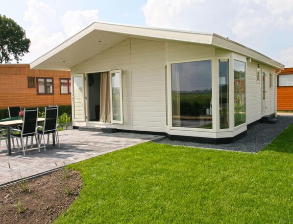 Una casa moderna con un patio, un'area pranzo e un'ampia porta scorrevole in vetro.