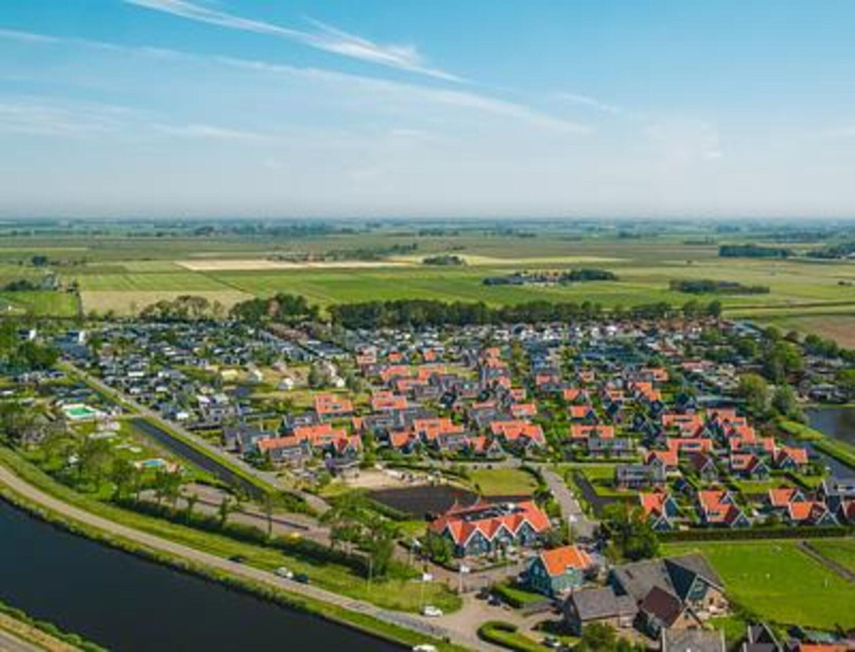 Een pittoresk rivierdorp met traditionele huizen, een kanaal en omliggende velden.