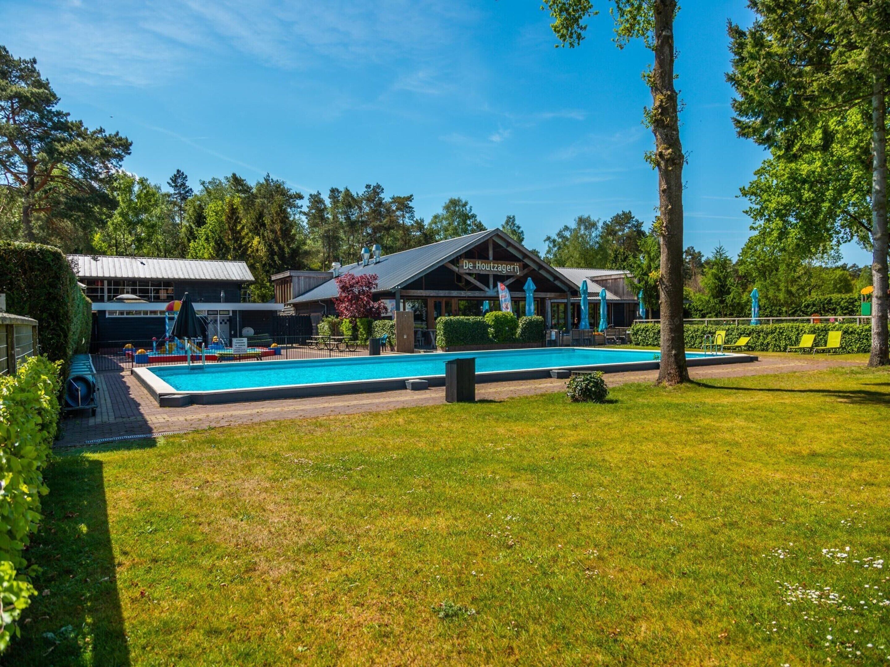 Ein Schwimmbeckenbereich mit einem Gebäude im Hintergrund, auf dem 
