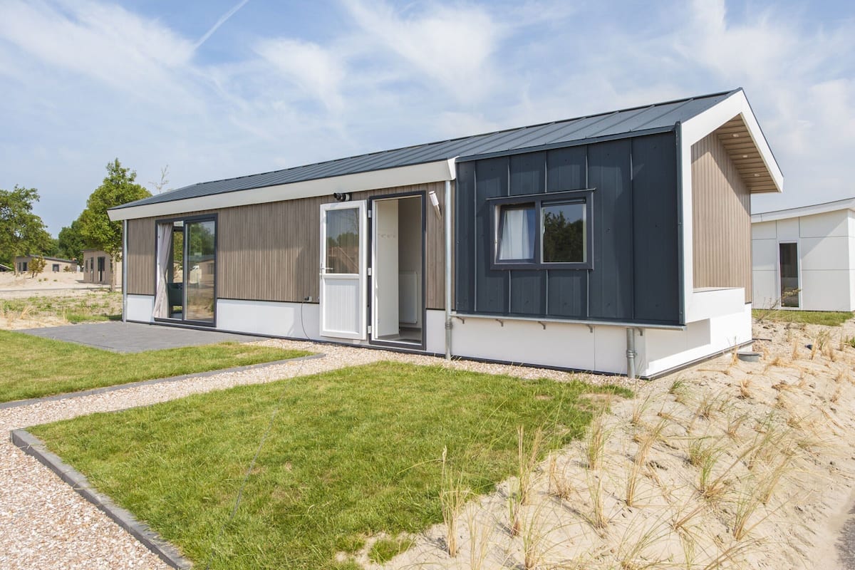 A modern, single-story building with a flat roof, large windows, and a covered outdoor area.