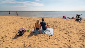 Una spiaggia sabbiosa con persone che si rilassano e un passeggino.