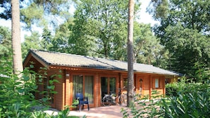 A wooden cabin with a porch, bicycles, and a small table. - Wooden Chalet Located in the Achterhoek (Lochem)