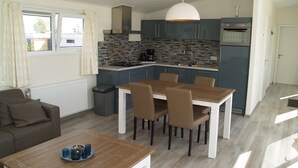 Una cucina moderna con zona pranzo, che include un tavolo con sedie, un divano e una finestra con tende.