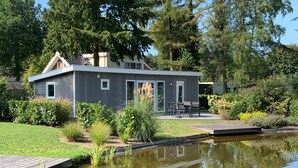 Una casa moderna con una veranda e uno stagno di fronte.