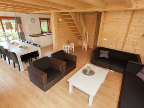 A spacious living area with a dining table, sofas, and a staircase leading to an upper level. - Wooden Holiday Home Near Brunssummerheide (Brunssum)