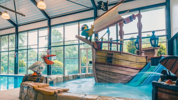 Zona de piscina con temática pirata, que incluye un naufragio y una estatua de sirena.