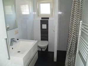 Bathroom features a bathtub, toilet, and shower, with a small window above the toilet.