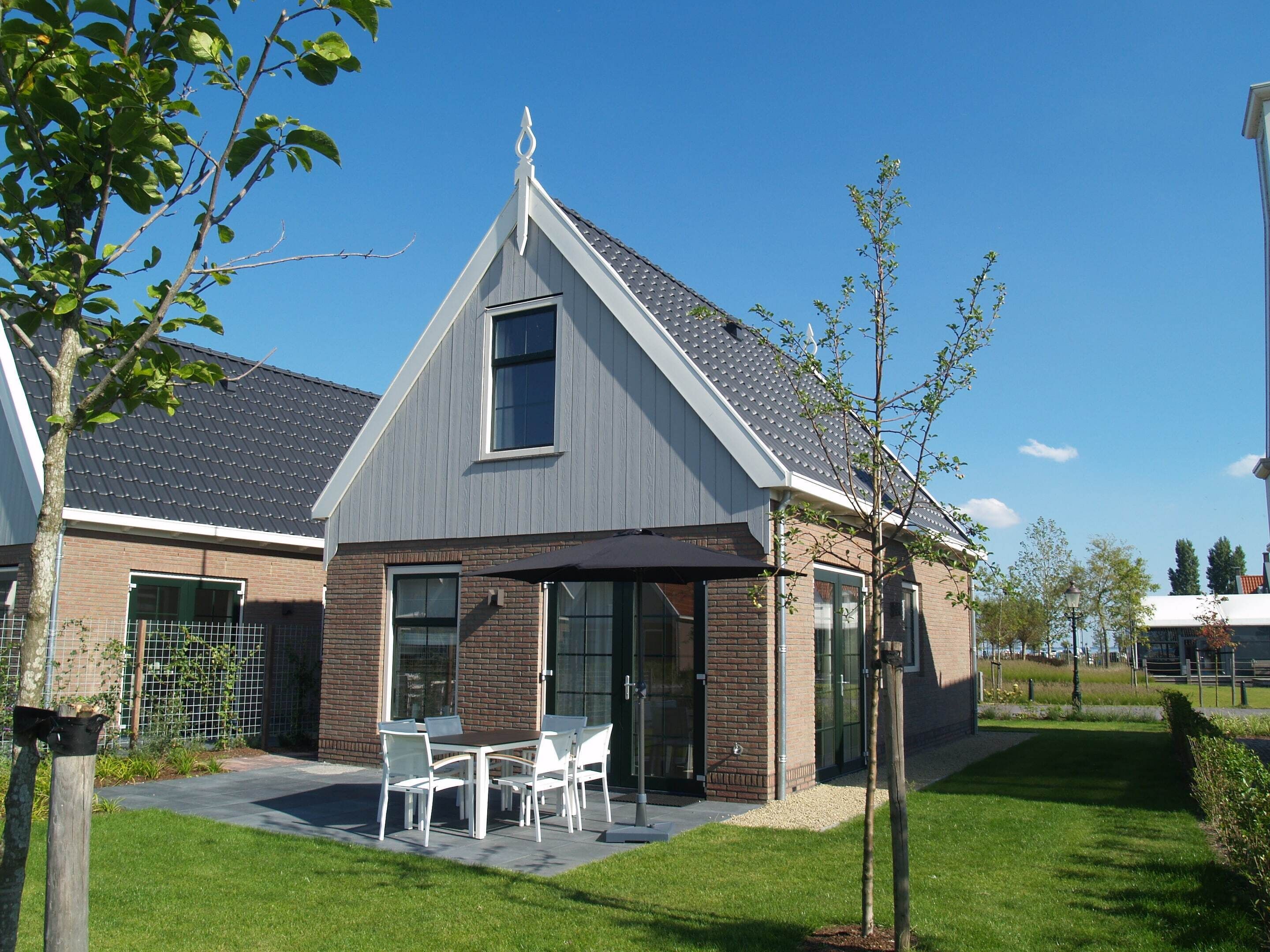 Een modern huis met een overdekte patio, een bakstenen gevel en een schuin dak.
