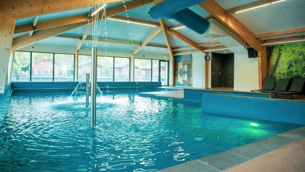 An indoor swimming pool with wooden beams, clear windows, and a view of the outside. - Tidy Furnished Chalet With a Dishwasher (Lochem)