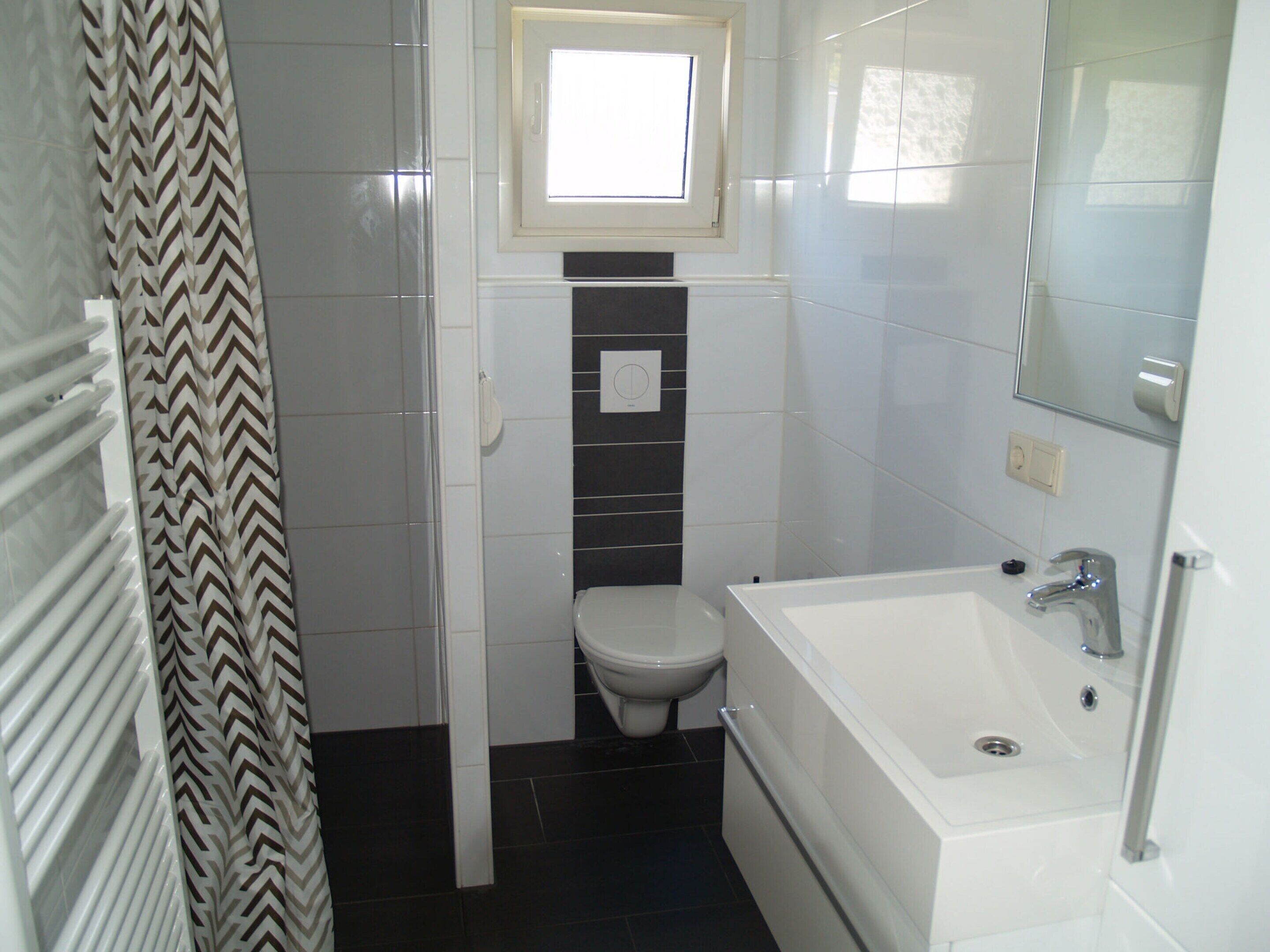 A compact bathroom with a toilet, a bathtub, and a shower.