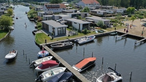 Une propriété située au bord d’un canal, avec des maisons modernes, un quai où sont amarrés des bateaux et une aire de jeux.