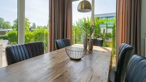 Un espace repas avec une table en bois, des chaises en cuir noir et un luminaire suspendu.