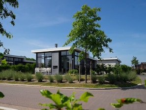 A modern building with a glass facade, surrounded by greenery and a paved area. - Luxury Chalet With a Dishwasher (Nunspeet)