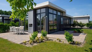 Une maison moderne dotée d’un patio, d’un espace salon extérieur et d’un jardin bien entretenu.