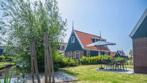 A house with a red-tiled roof, a wooden deck, and a small pond. - Dutch Family Geataway in West-graftdijk (West-Graftdijk)