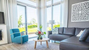 Ein modernes Wohnzimmer mit einer Couch, einem blauen Sessel, einem runden Couchtisch und einem Kamin.