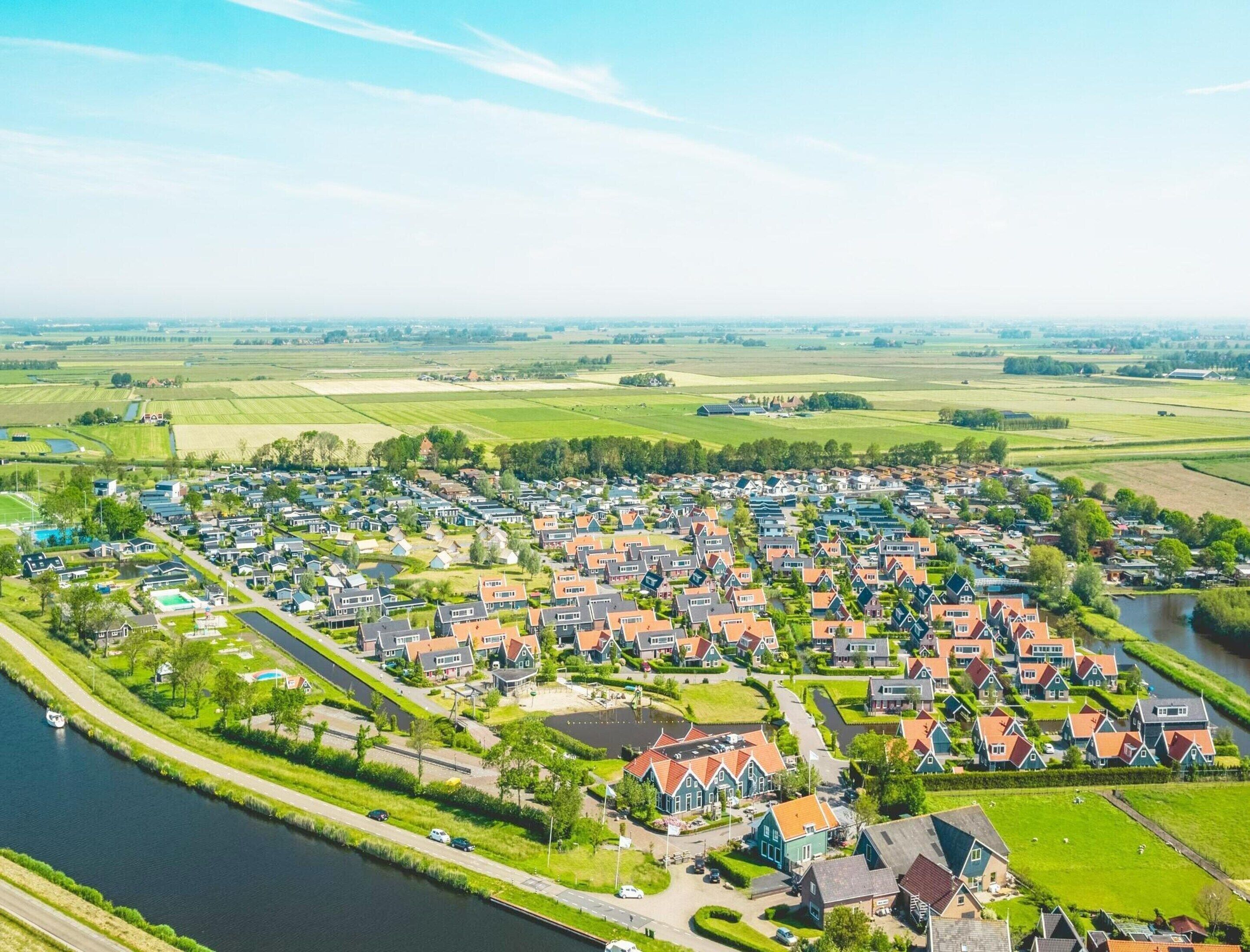 A residential area with houses, a river, and green fields.