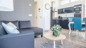 Ein modernes Wohnzimmer mit einer Couch, einem runden Couchtisch und einem Essbereich mit Stühlen.
