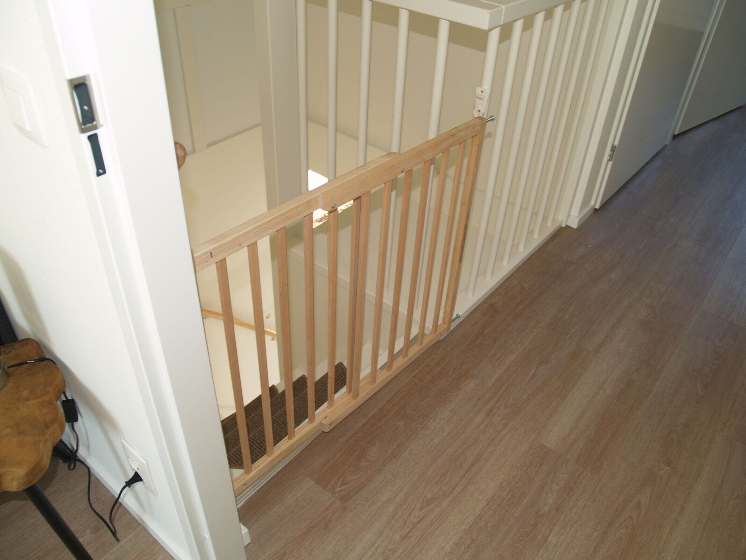 A wooden baby gate at the top of a staircase.