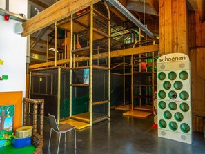 A multi-level indoor play area with wooden structures and netted climbing areas. - Cheerful Mobile Home Near Park De Veluwe (Otterlo)